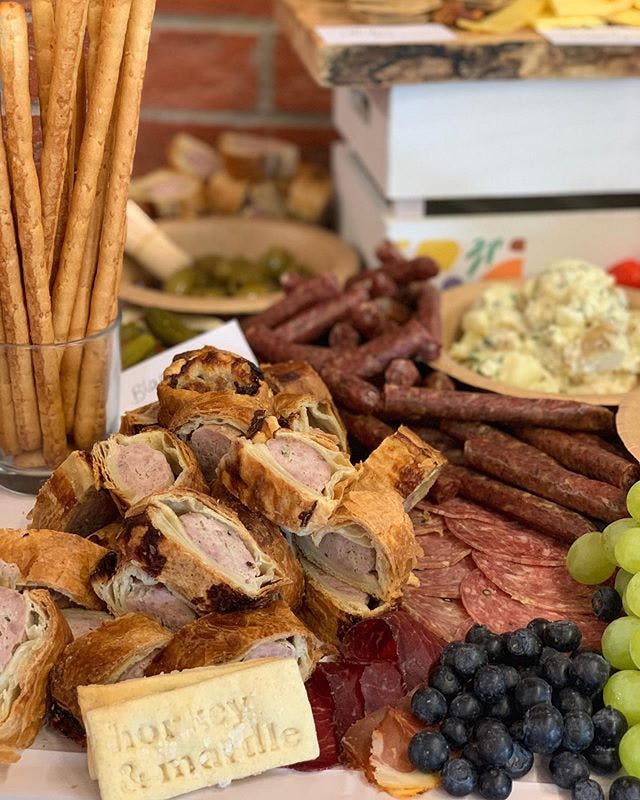 Grazing table spread of pork pies, cooked meats grapes and breadsticks